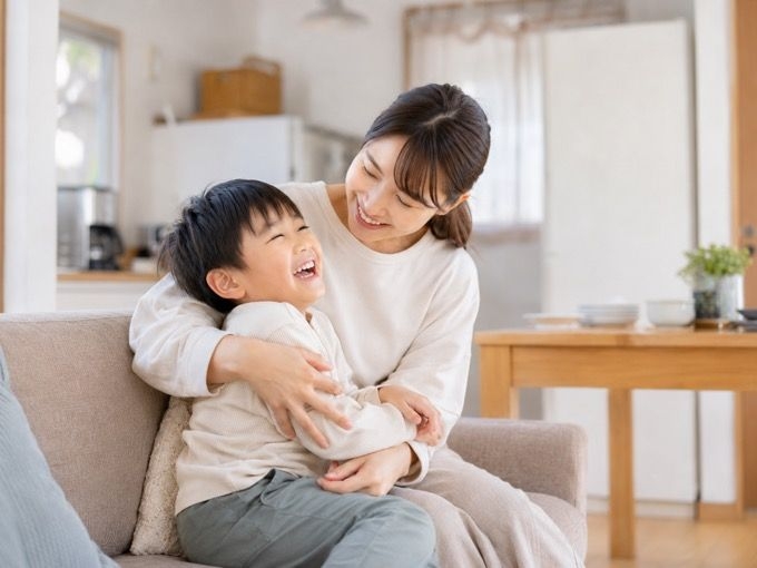 ソファで抱き合って笑う母親と子ども